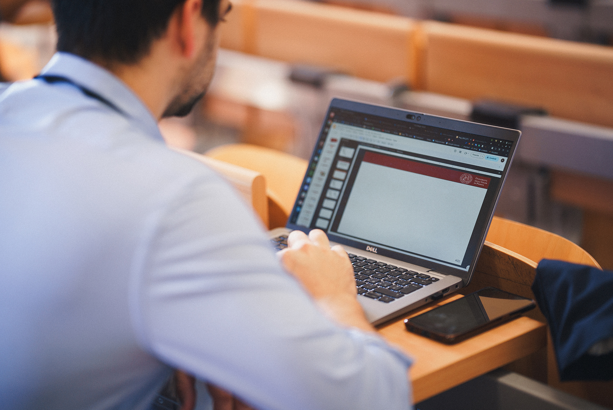 A focused man sitting at a table, engrossed in his work on a laptop.